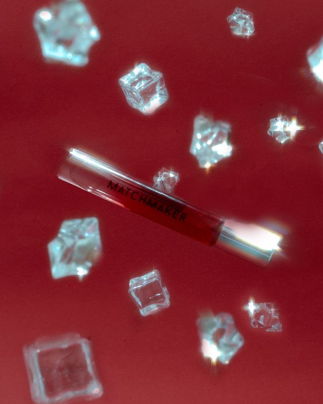 Matchmaker pheromone perfume falling through the air against a red backdrop and crystal ice cubes
